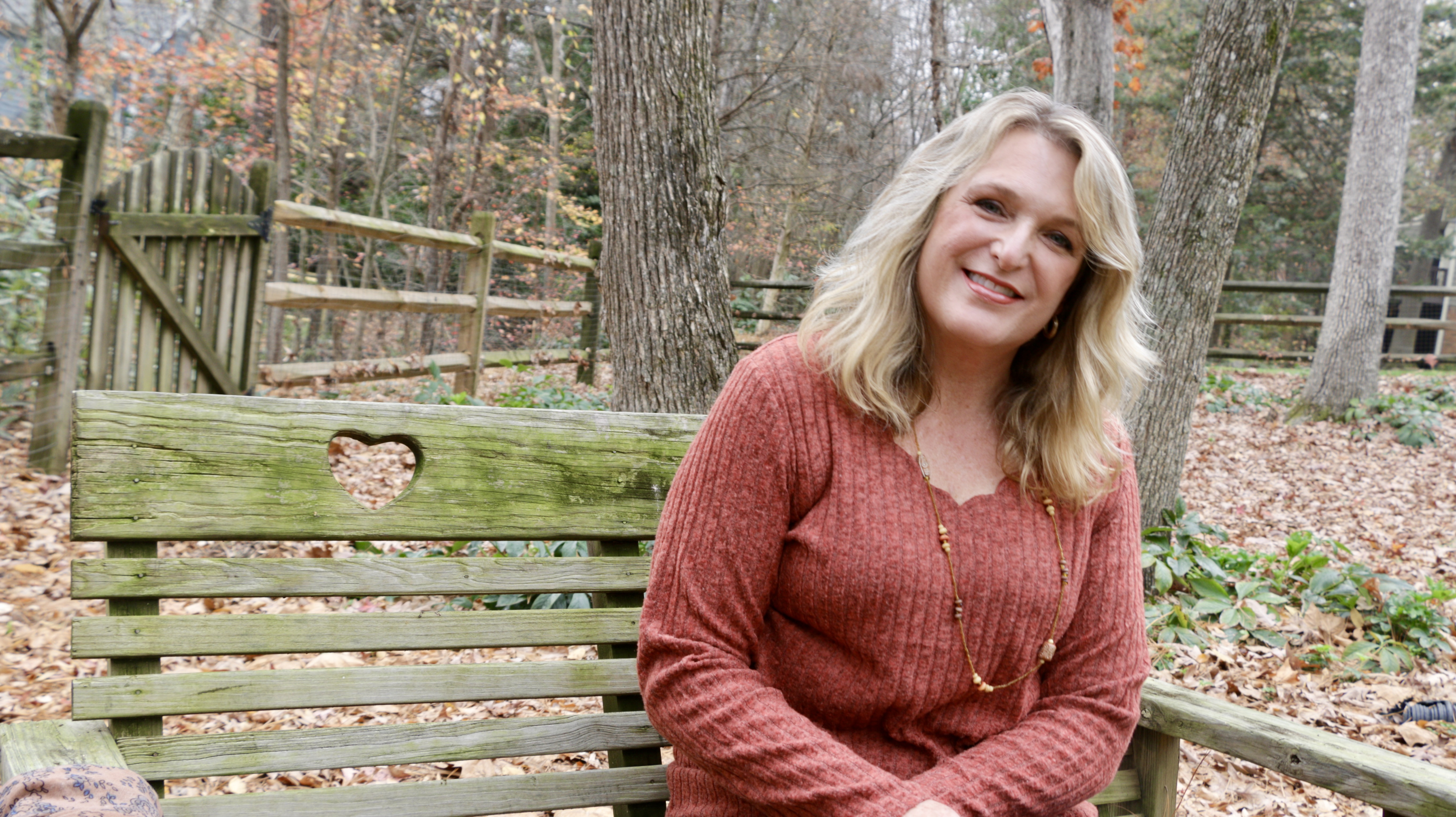 Janet Cooper Haas, a Clinical EFT practitioner in Charlotte, NC, sitting on a wooden bench with a heart cutout, symbolizing the compassionate inner child healing she brings to her intergenerational trauma work.